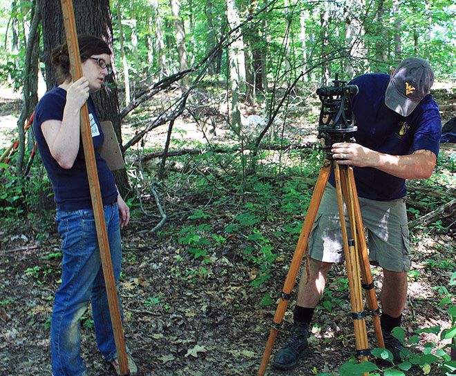 Two people setting up survey equipment