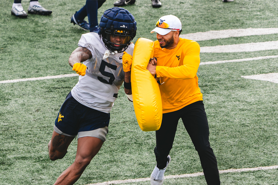 Coach works on a drill with a football player