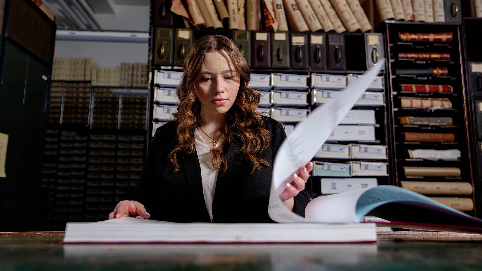 Bella Herrod flips through a book of deed records