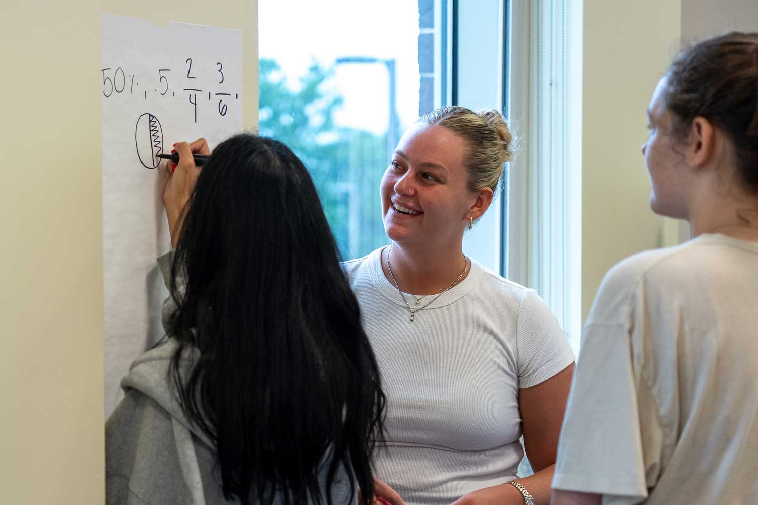 Student working a problem on an erasable board