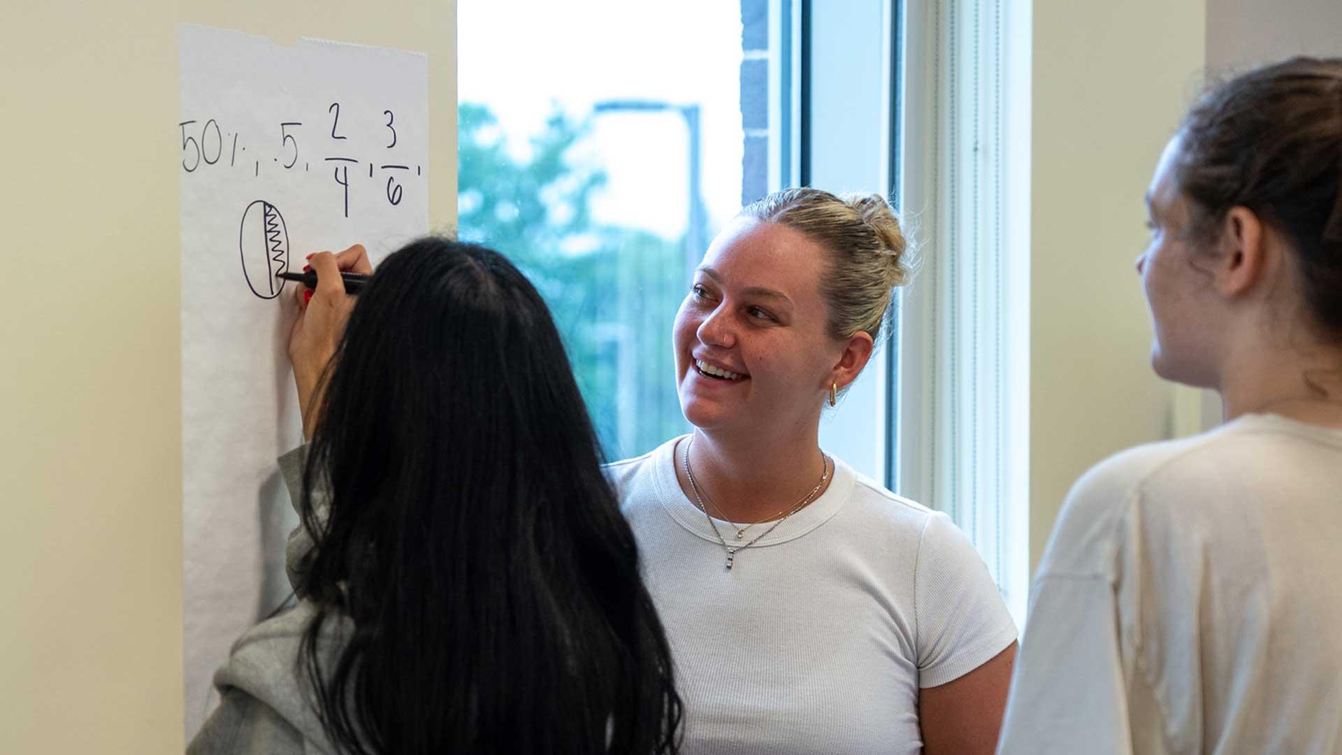 Students work a math problem on a the classroom wall