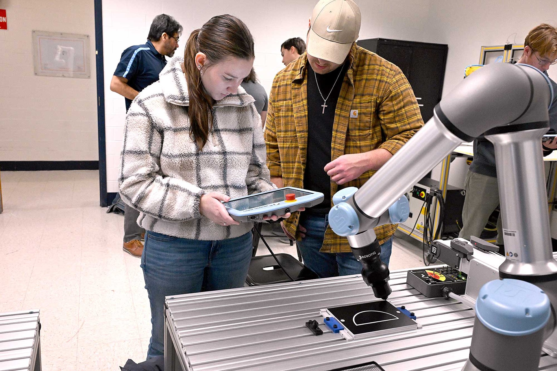 Students us a tablet to control a robotic arm.