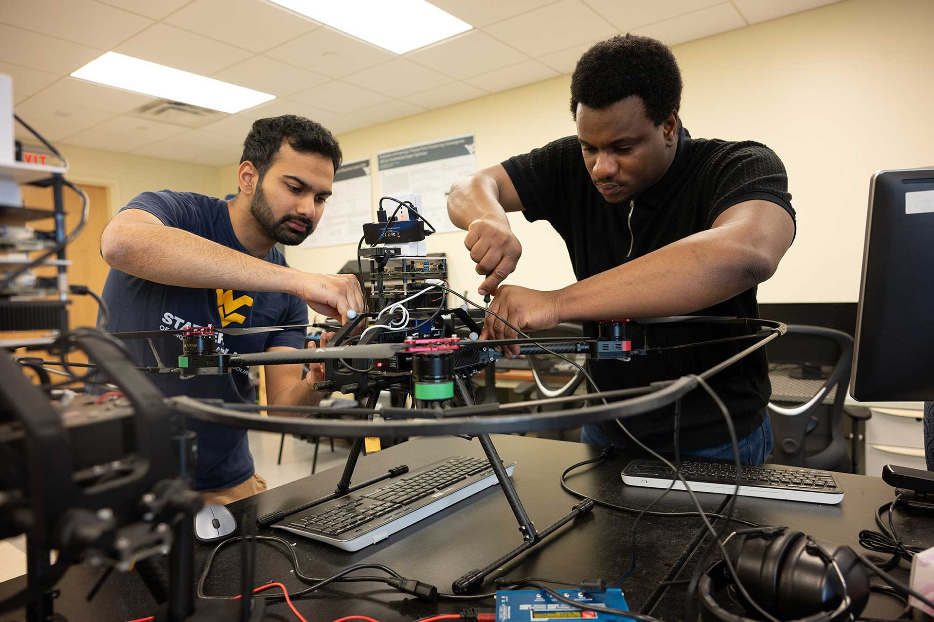 Two students tighten screws on a piece of equipment in the navigation lab