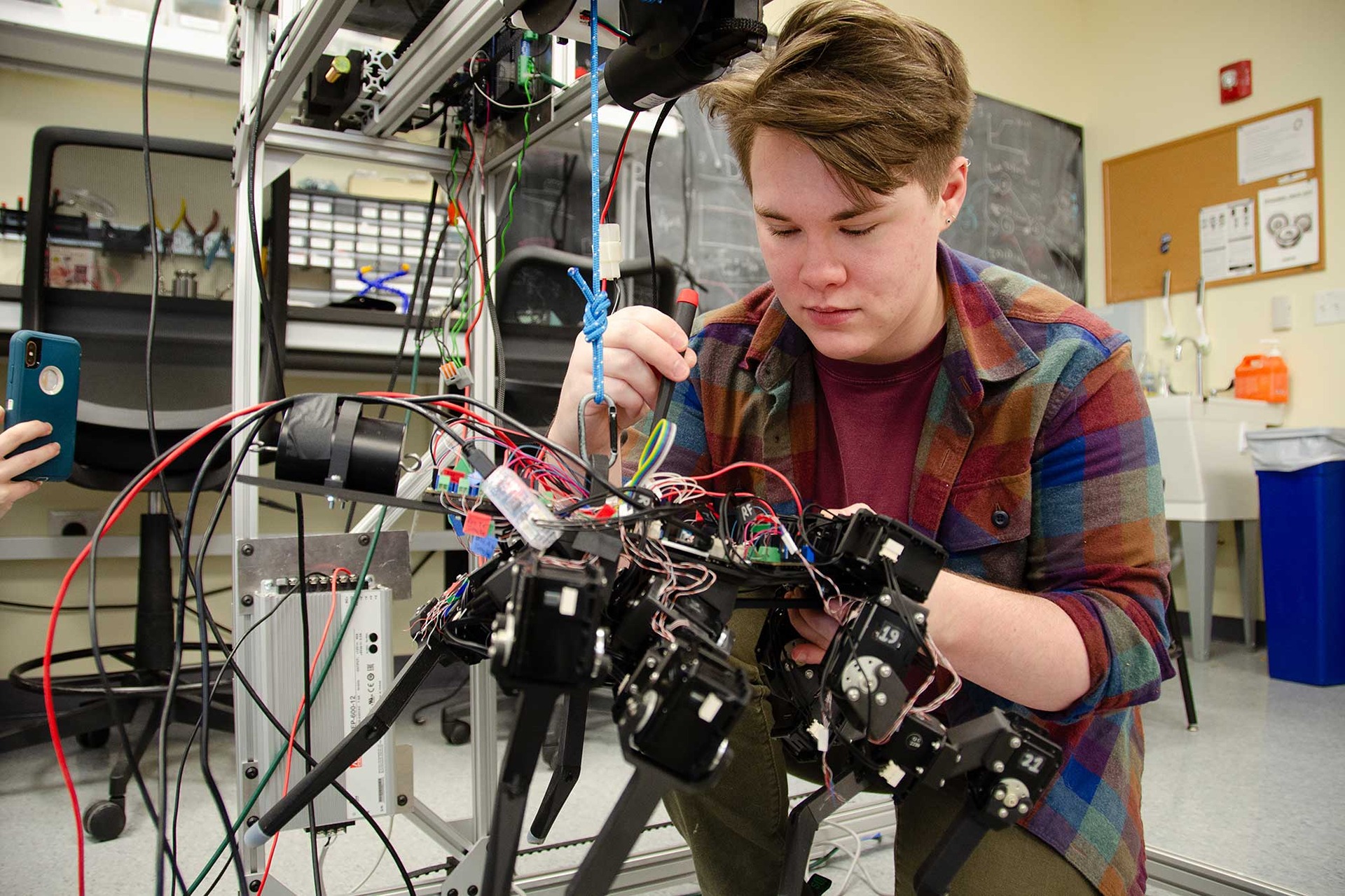 Student positions a screwdriver while working on a robot.