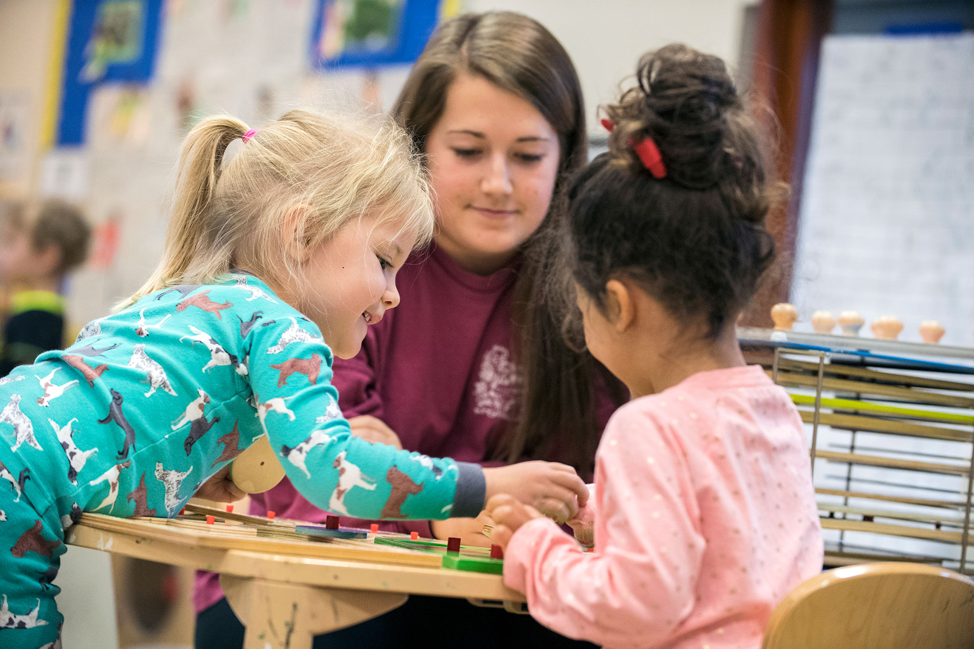 Two children playing as a staff member looks on