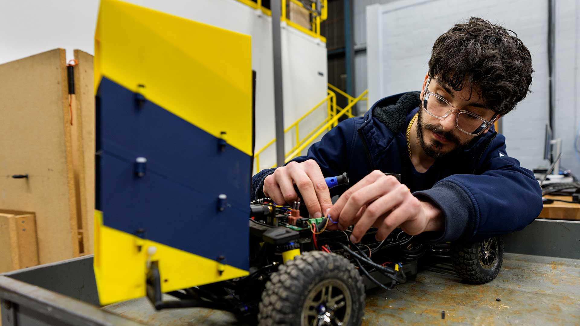 Andrew Sarver checks parts on a small autonomous racing car