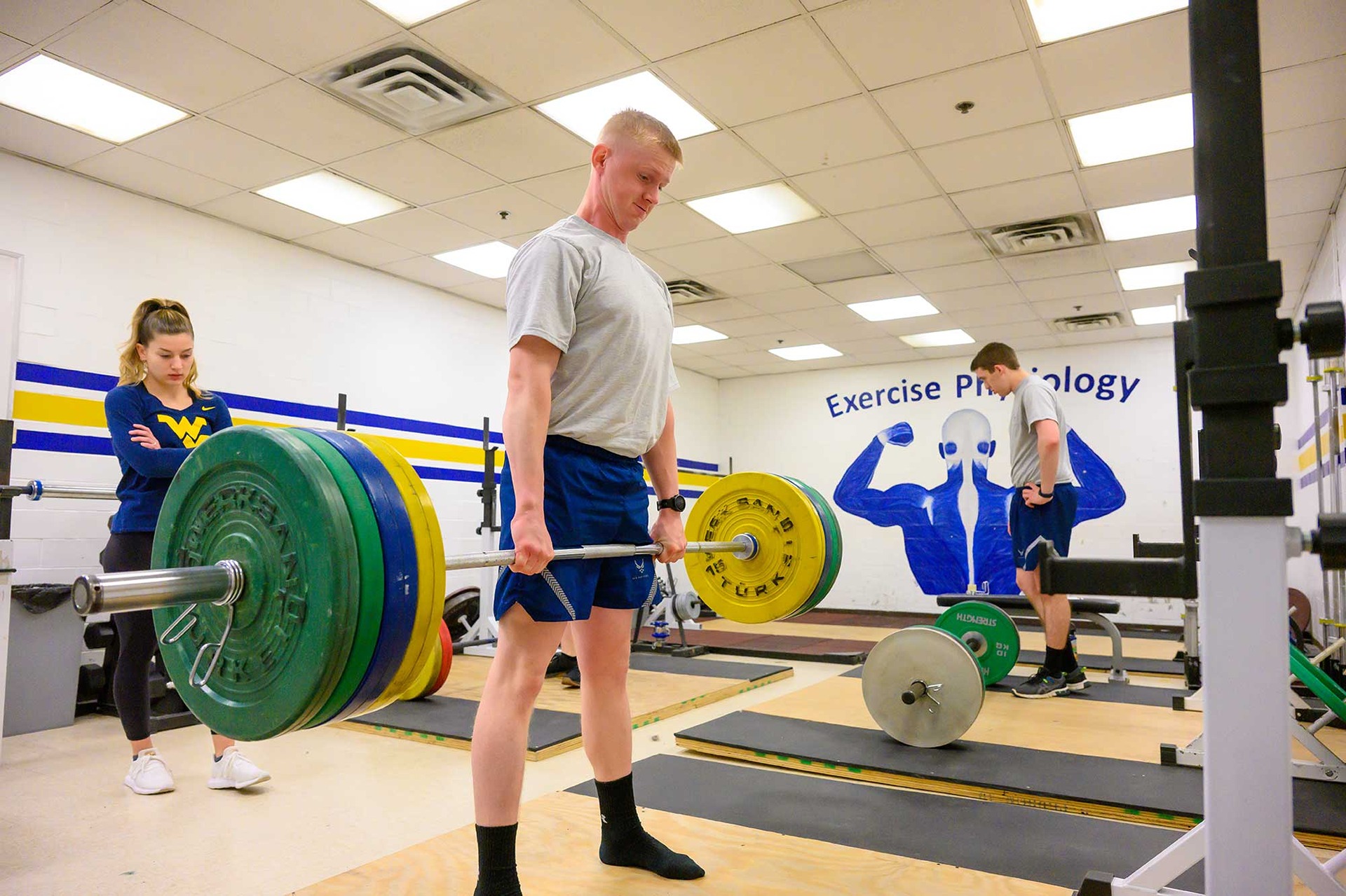 Student watches another student lifting weights