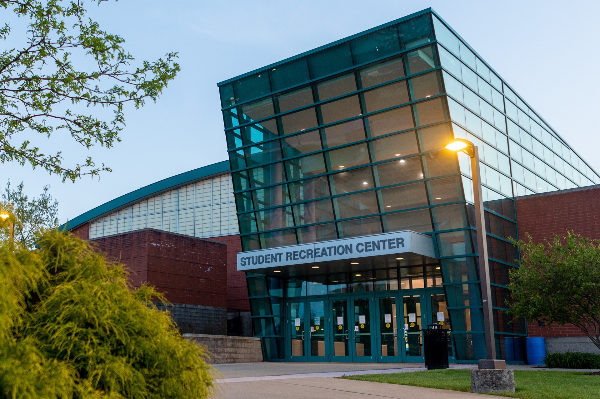 Windowed and brick exterior of Student Recreation Center. Shows the entrance facing the Health and Education Building.