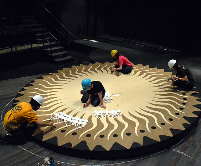 Students painting a design on the floor of a stage