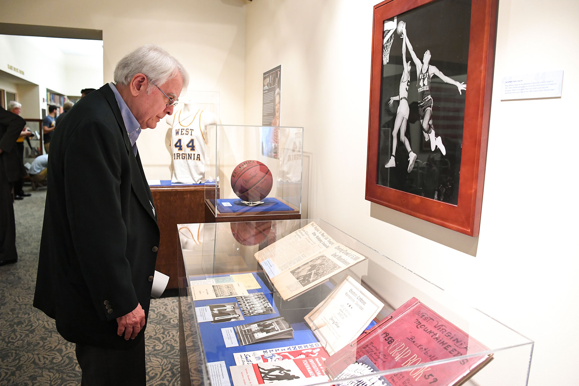 Person looking at photos and other objects on display from the Jerry West collection