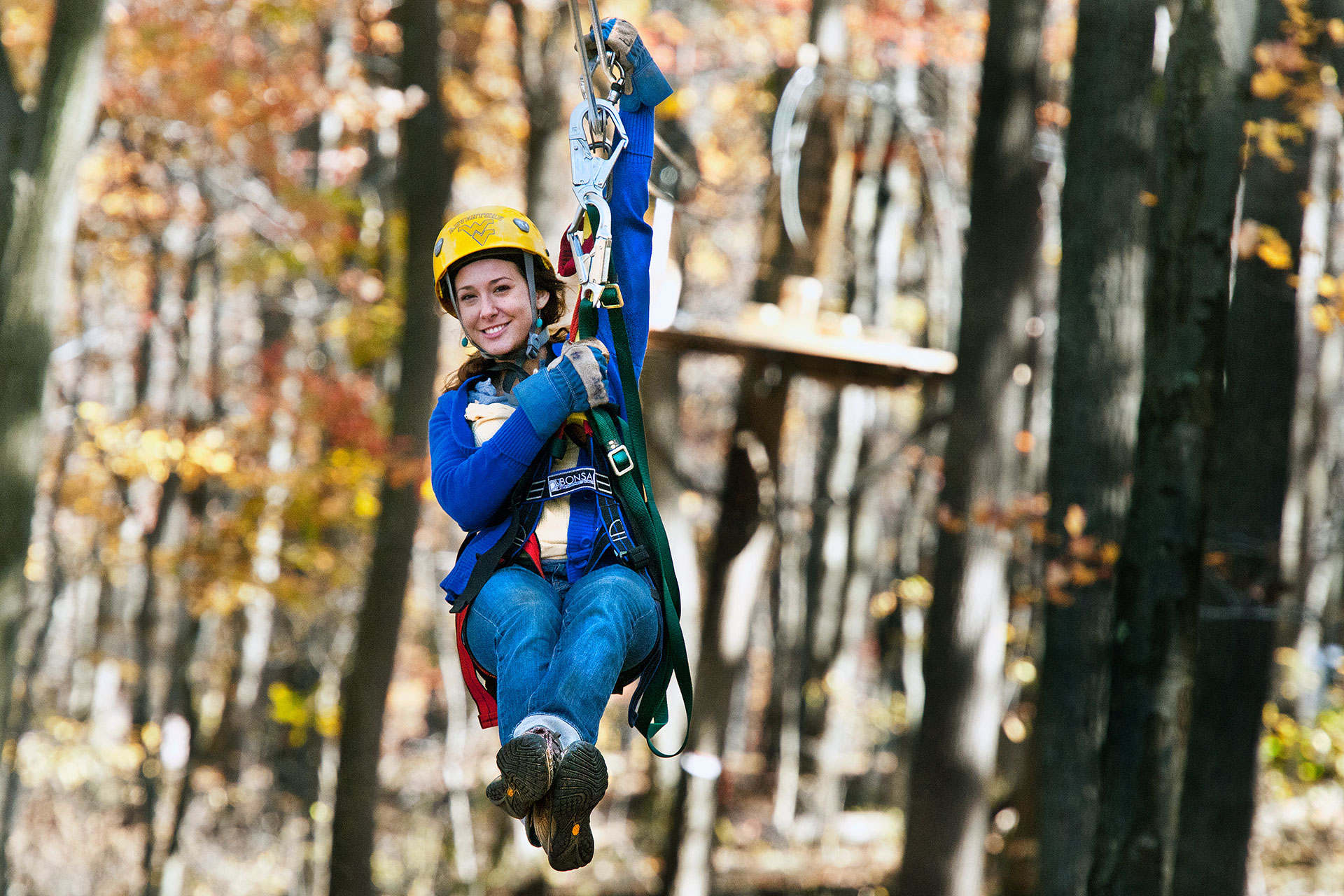 Person riding on a zip line through the University forest