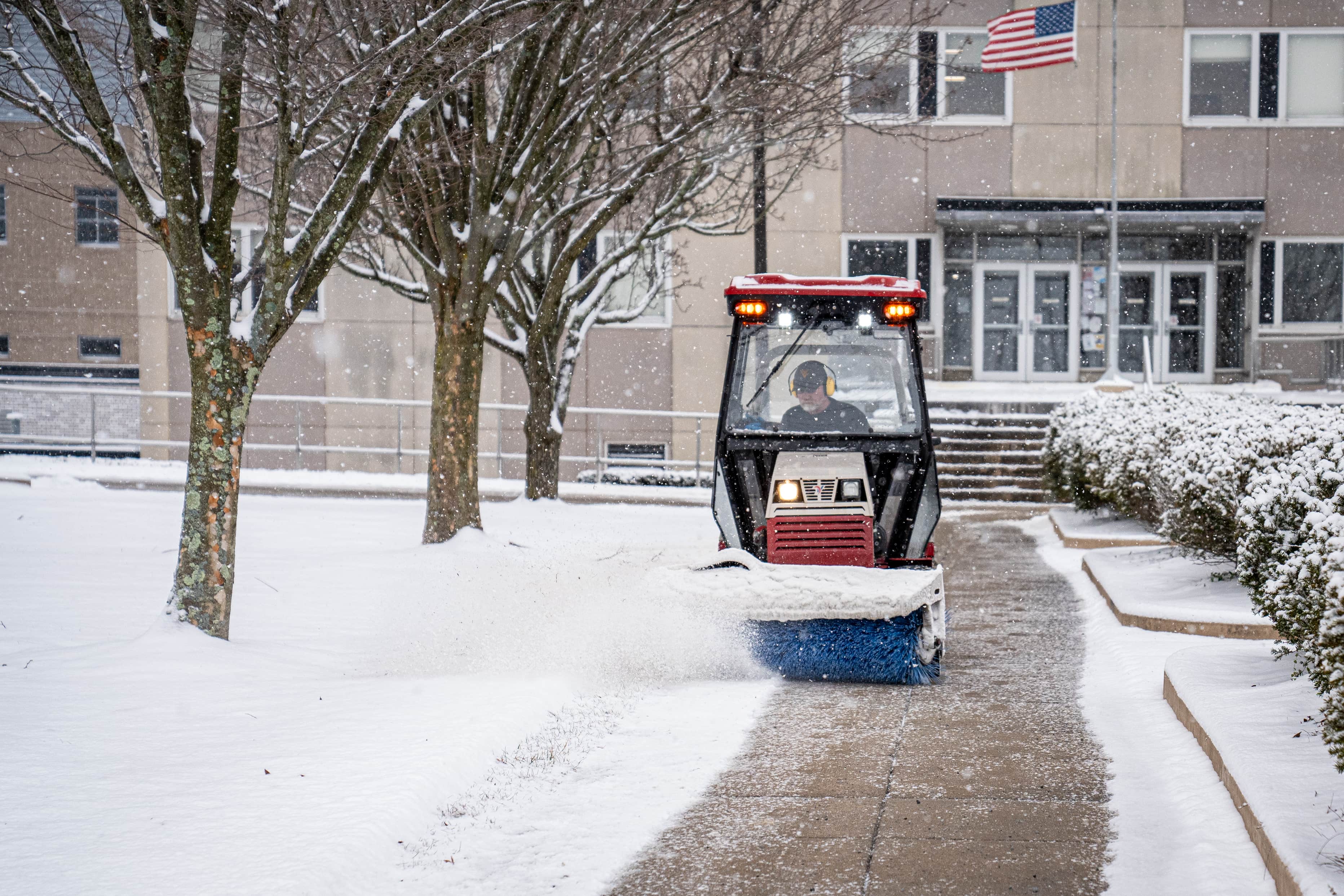 a snow sweeper clearing sidewalks on a snowy Evansdale campus.