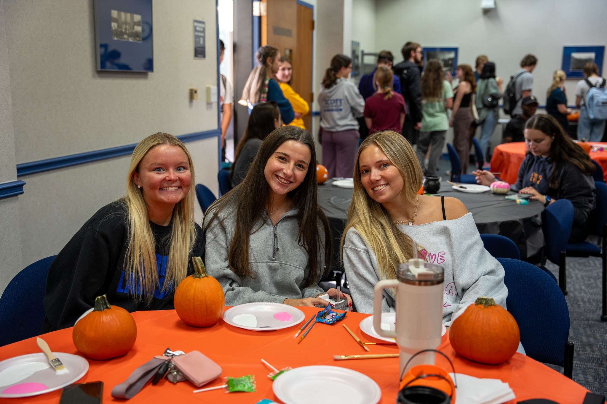 Three students painting pumpkins together in the Mountainlair for Halloween 2025
