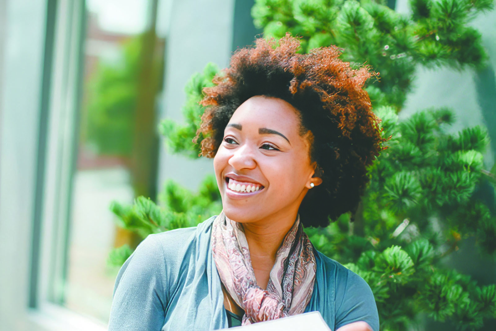 Cortina Caldwell smiles while holding a laptop outdoors.