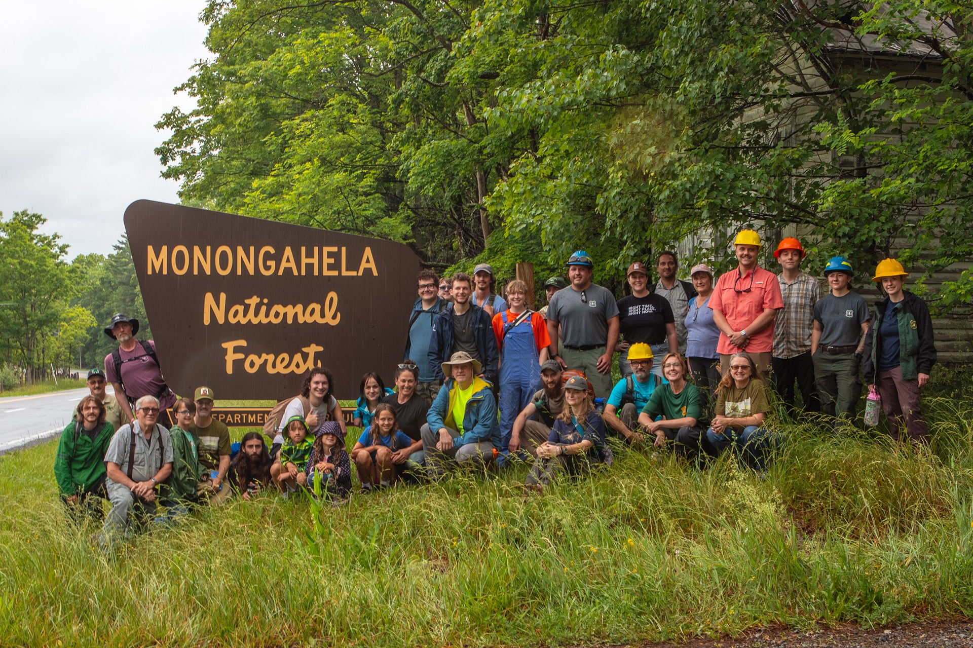 Trail workshop participants gather beside a Monongahela National Forest sign.