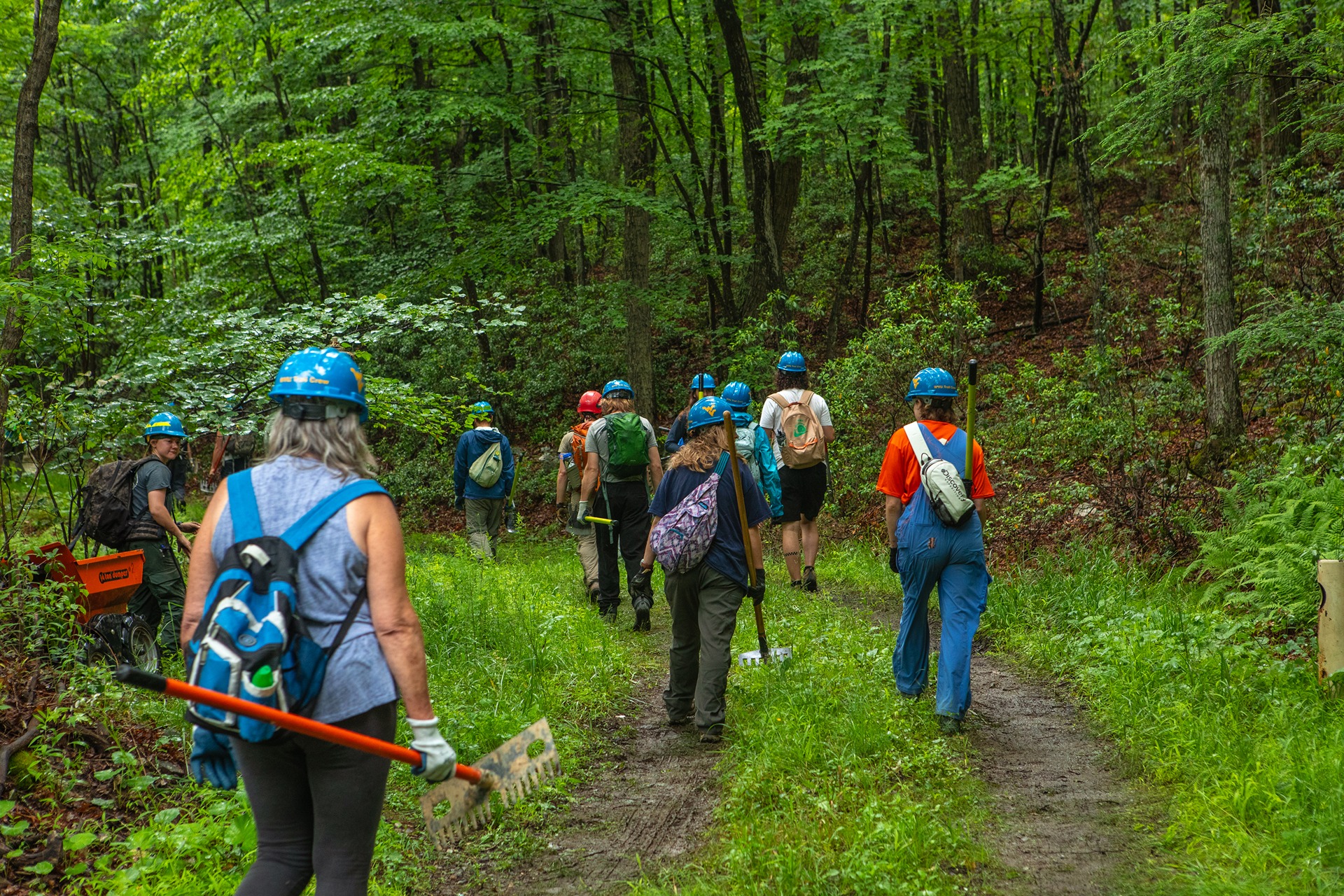 Trail Training and Education participants carrying tools hike to a work site.