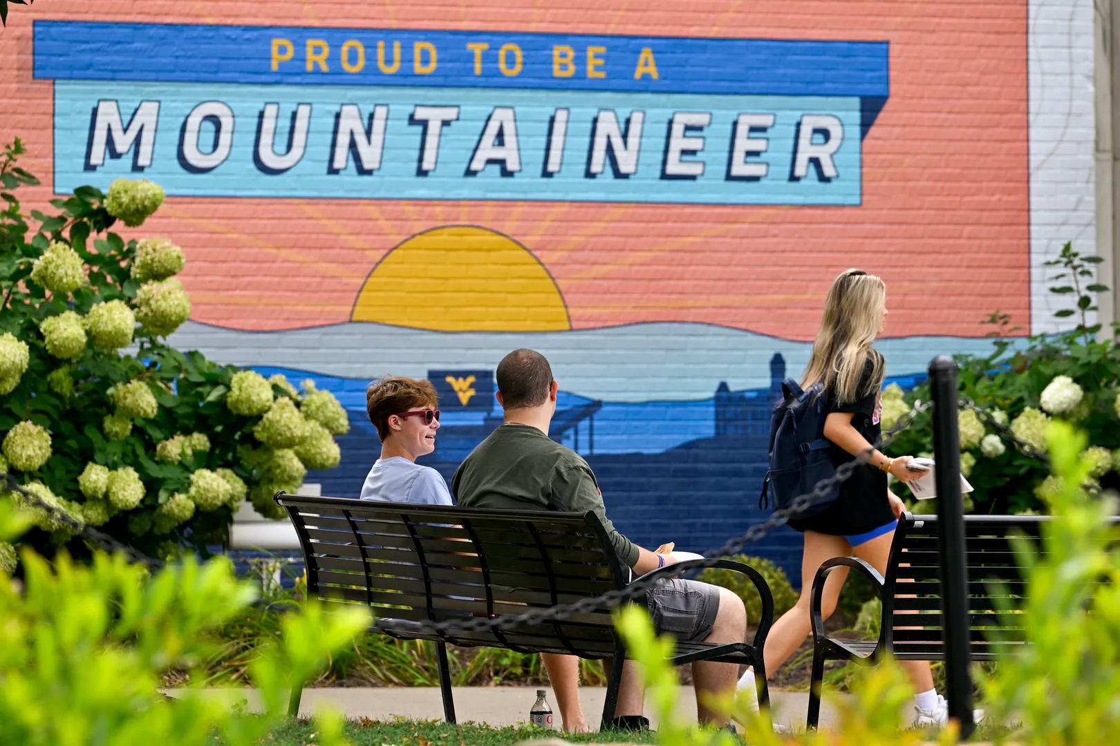 WVU students catch up on a bench near the Mountainlair on campus at the start of the school year.