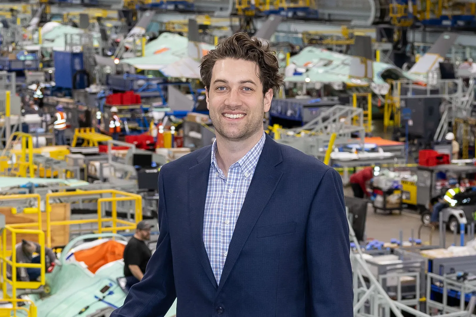 WVU Online Alumni James Brooks posed by a work floor where jets are being worked on