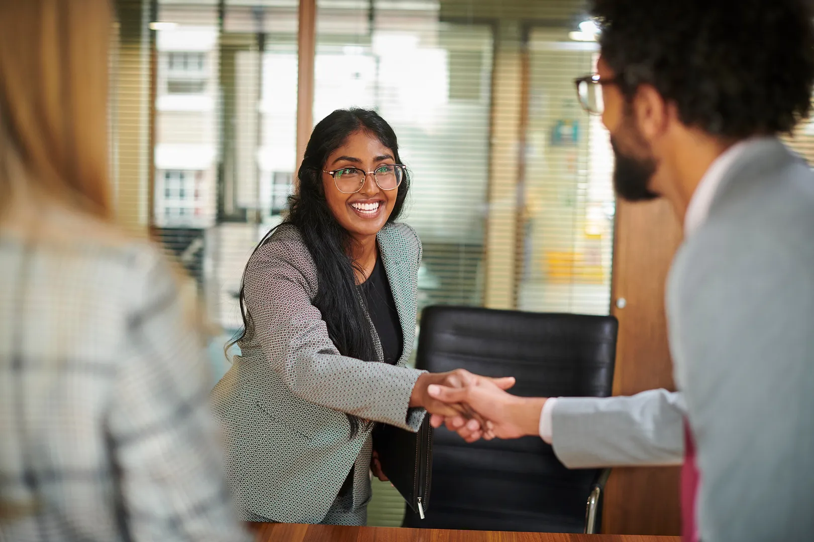 Woman entering a job interview and shaking hands with the interviewers